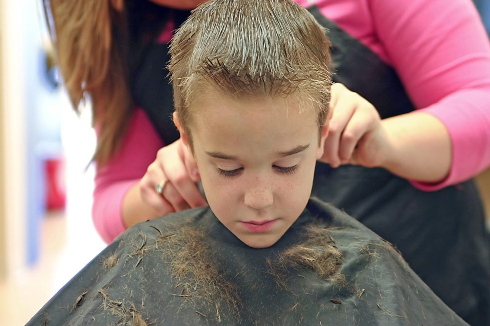 a hair stylist is cutting the hair of a child
